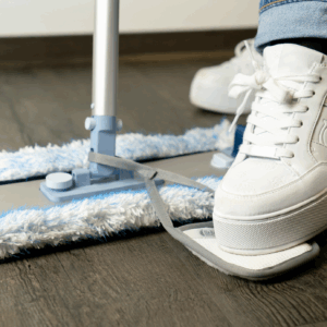 Osoba naciska Scrubby stopą na plamę, skutecznie usuwając zabrudzenie.